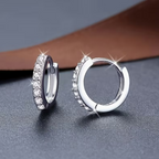 Lumière Pavé Huggie Hoop Earrings – silver huggie hoops resting on wooden surface with white rose